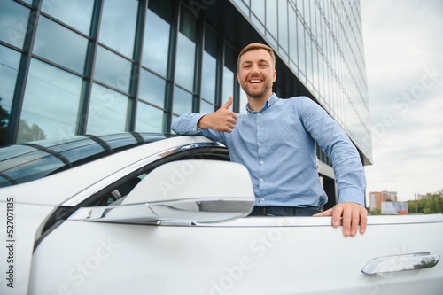 handsome young businessman standing near his car outdoors.