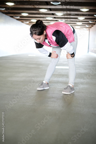 Young beautiful girl in pink sportswear with hood stretching outdoor