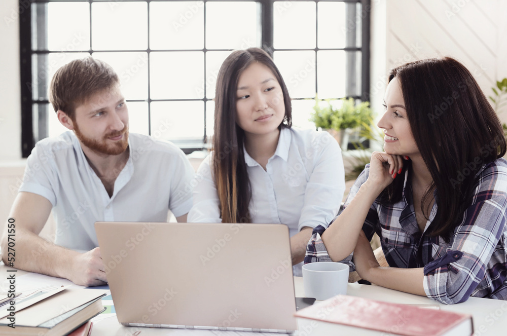 Three young business people working at office with paperwork using laptop Three young business people working at office with paperwork using laptop