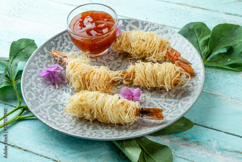 Deep fried prawns in kataifi dough in a round plate. photo