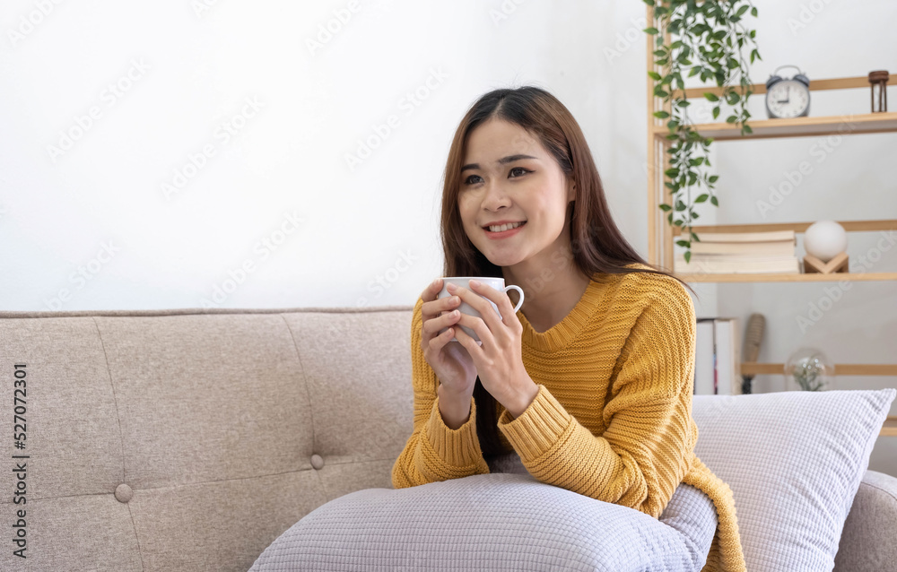 Young asian woman drinking coffee on a sofa bed at home Young asian woman drinking coffee on a sofa bed at home