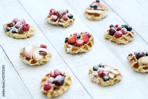 Breakfast of tasty mini Waffles with berries on a wooden surface
