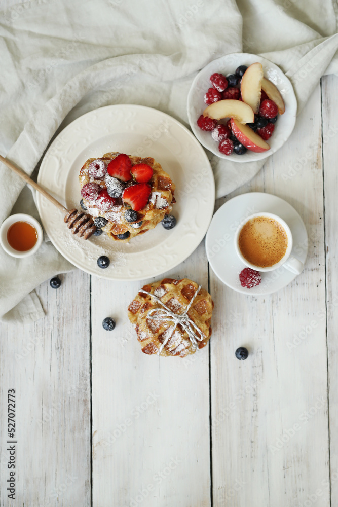 Delicious breakfast consisting of sweet waffles with berries and a cup of coffee on the table Delicious breakfast consisting of sweet waffles with berries and a cup of coffee on the table