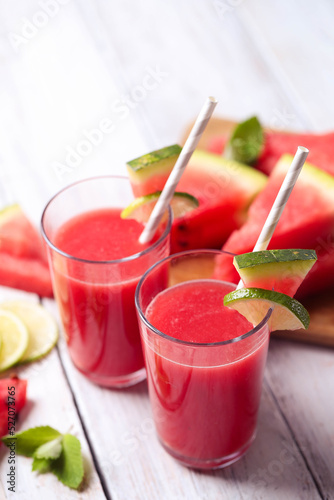 Watermelon smothie and slices with lime on a wooden surface