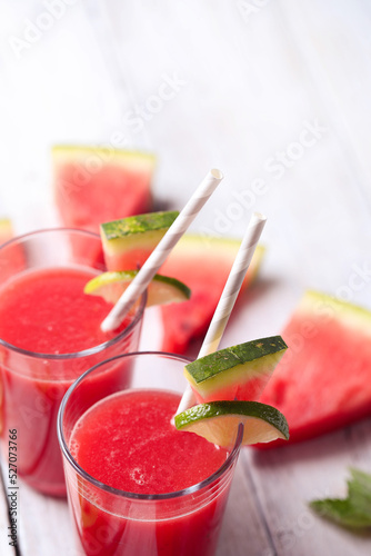 Watermelon smothie and slices with lime on a wooden surface