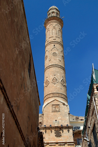 View from below to the top on ornate minaret of the Mardin Grand Mosque from the street in the historic part of the city of Mardin in the Southeast Anatolia region of Turkey