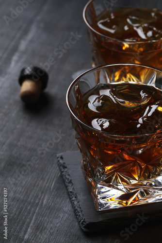 Two glasses of whiskey with ice on a stone table.