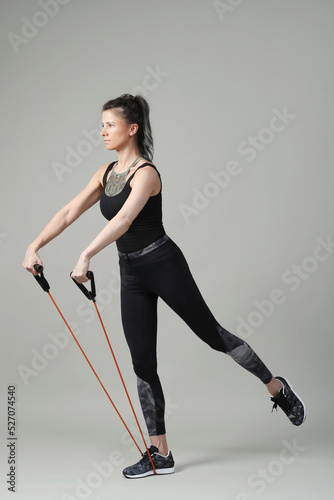 A young,sporty,brunette woman doing fitness exercises with resistance band 