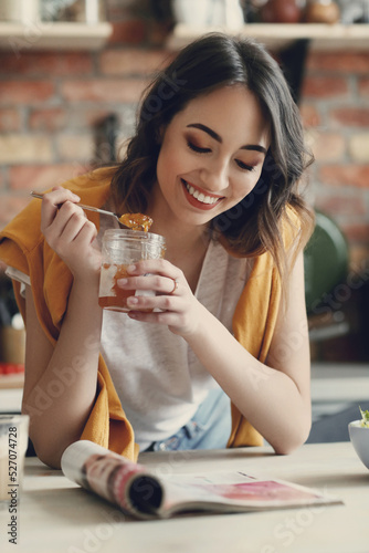 Woman at homeYoung, beautiful, charming woman eating delicious jam in the kitchen at home
