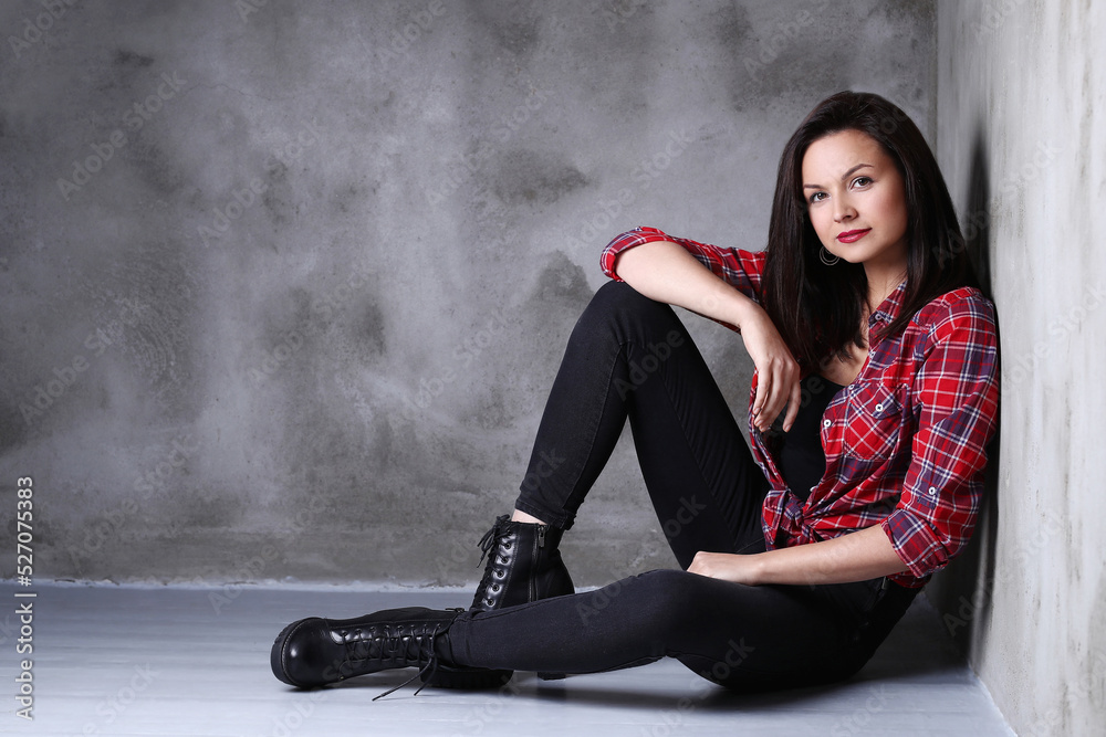 Photo of gorgeous , adorable , brunette woman in heels sitting on the floor isolated on dark color background