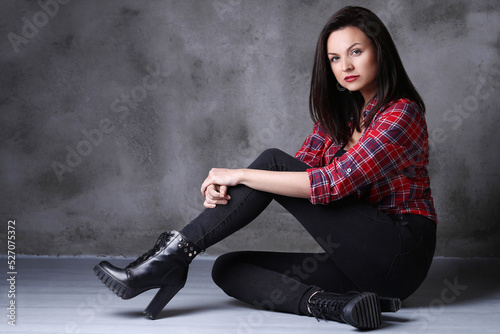 Photo of gorgeous , adorable , brunette woman in heels sitting on the floor isolated on dark color background