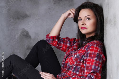 Close-up photo of gorgeous , adorable , brunette woman in black jeans sitting on the floor isolated on dark color background