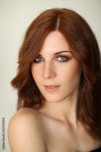 Close-up photo of a beautiful redheaded woman looking at the camera on a marble background