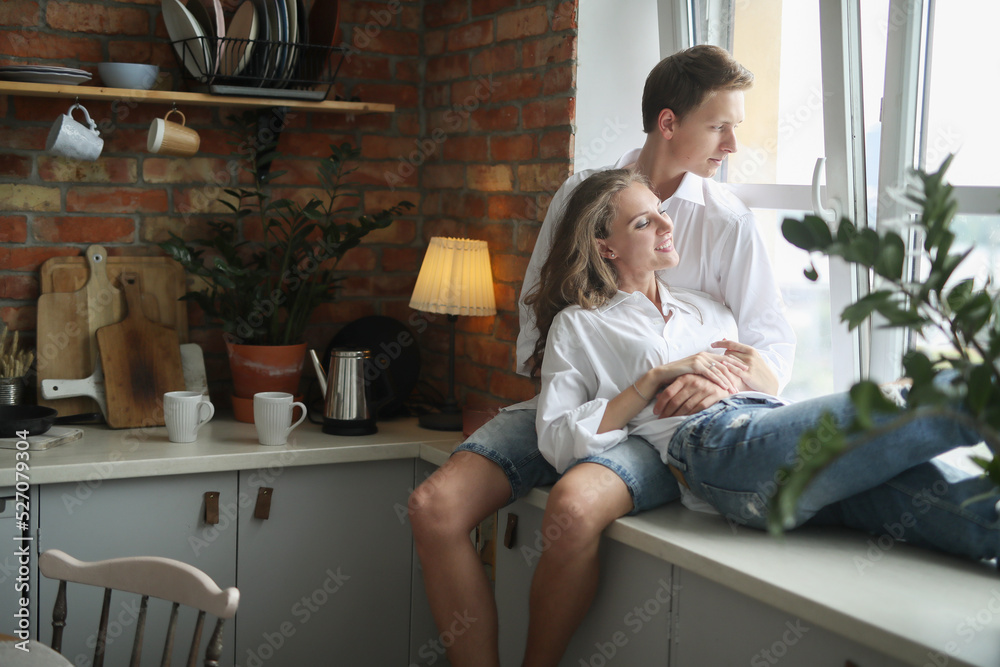 Photosession of beautiful,young couple lying and hugging on the windowsill in the kitchen room Photosession of beautiful,young couple lying and hugging on the windowsill in the kitchen room