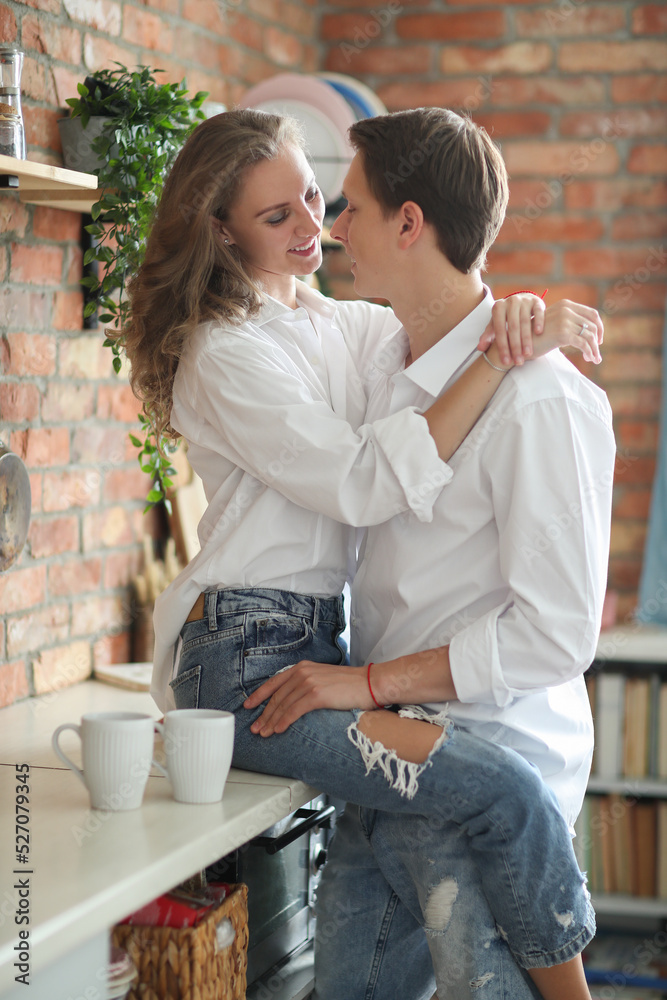 The woman on the kitchen table hugging her boyfriend’s neck