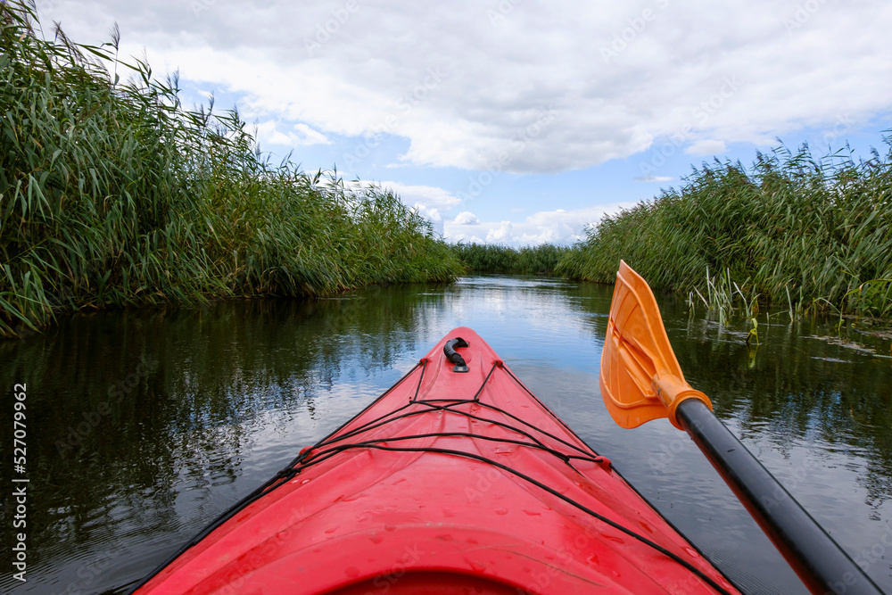 Kayaker point of view. Kayak bow with a view on the river and rushes. River kayaking concept. Active vacations in wild nature.