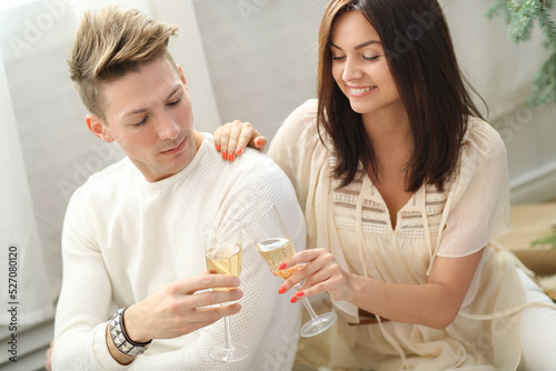 Young man and woman holding glasses of white wine and resting at a party