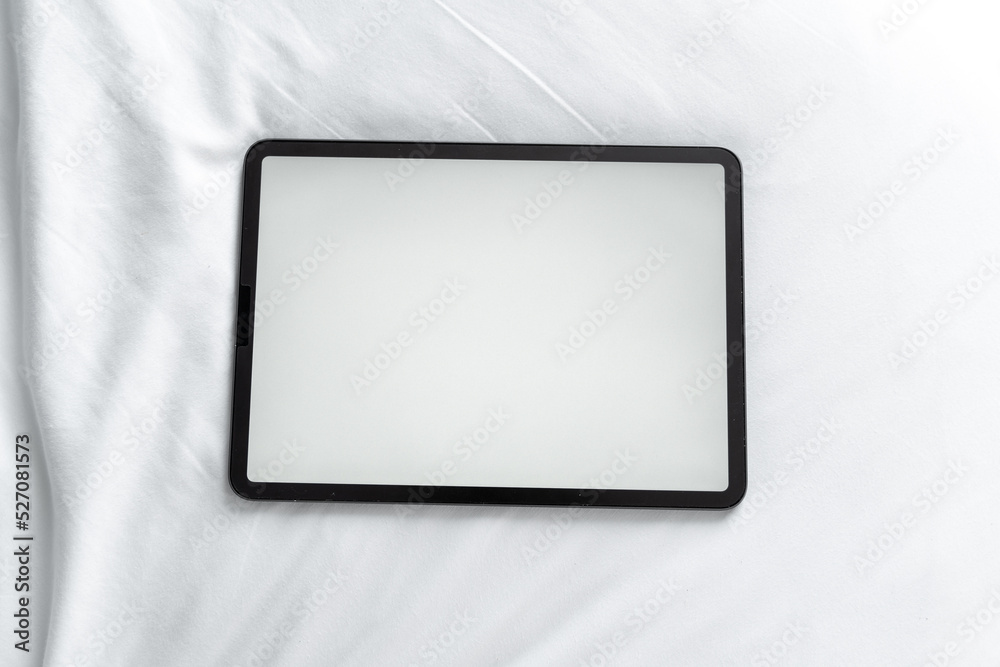 Top view tablet with blank desktop white screen white bed at home, crumpled beige blanket, Overhead shot Top view tablet with blank desktop white screen white bed at home, crumpled beige blanket, Overhead shot
