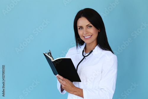 Professional,confident female-doctor with stethoscope filling up a form of patient on a blue background.