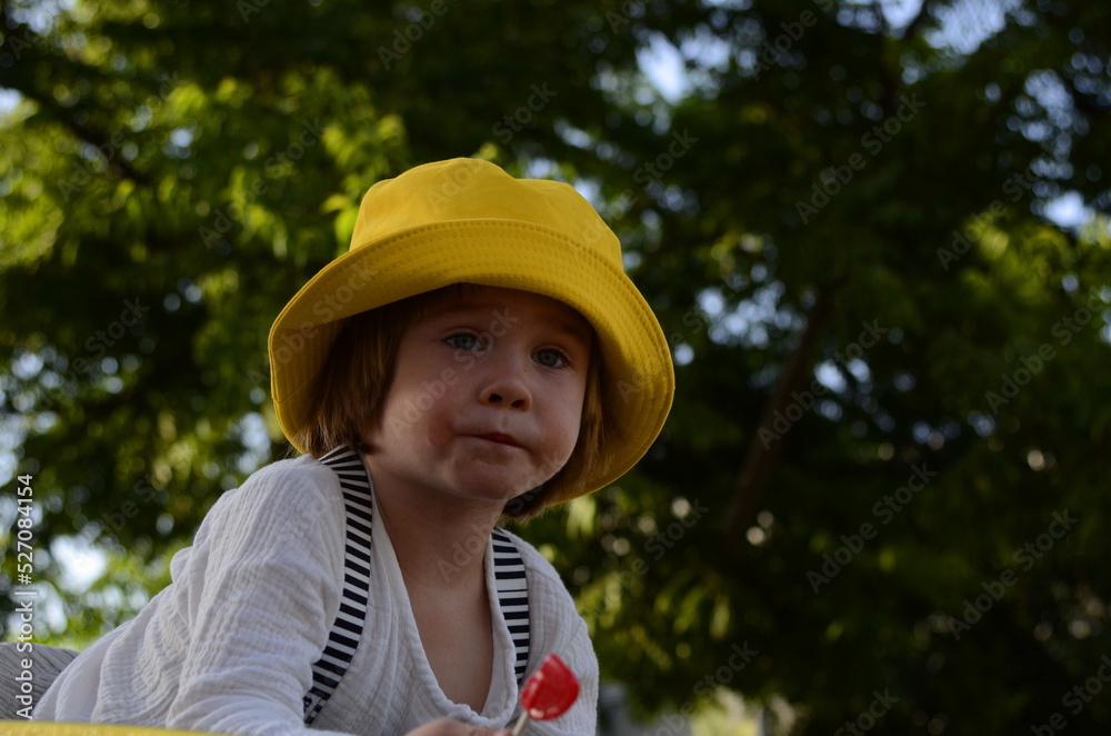 Portrait of a cute boy in a yellow panama hat. A cute child rejoices in the summer. Concept: travel to the resort, holidays with children, kindergarten, holiday, birthday.