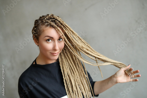 Close-up portrait of a young, beautiful woman with dreadlocks standing against stone background.