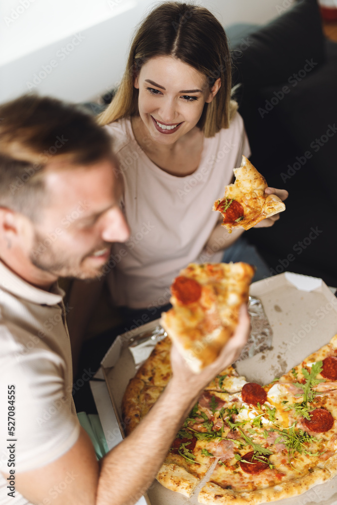 Happy young couple eating pizza for lunch in the living room Happy young couple eating pizza for lunch in the living room