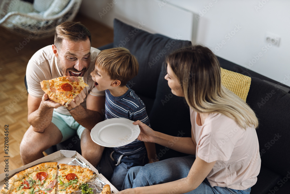 Happy father and son enjoying while eating pizza at home Happy father and son enjoying while eating pizza at home
