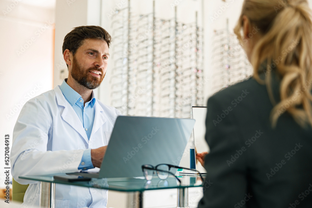An ophthalmologist consults a client at his workplace in an optician's shop An ophthalmologist consults a client at his workplace in an optician's shop