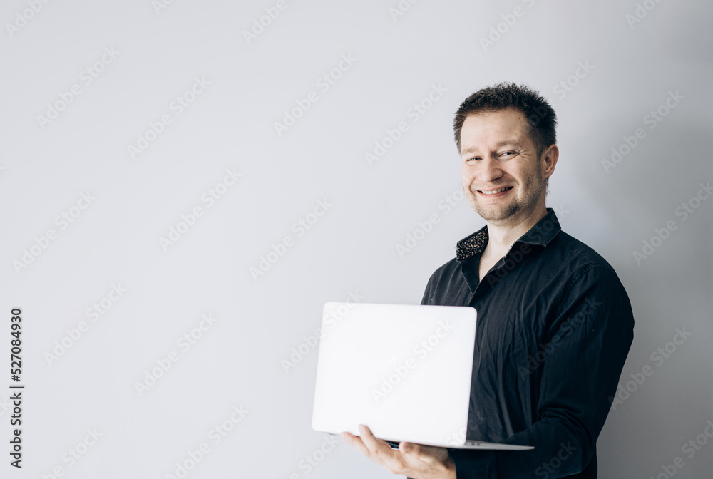 Confident IT specialist in black shirt holding laptop and smiling. Confident IT specialist in black shirt holding laptop and smiling.