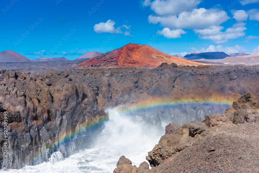 Beautiful rainbow caused by the crashing of the Ocean waves against the volcanic cliffs of Los Hervideros, Lanzarote,  Canary Islands, Spain