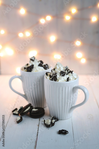 Side view of chocolate frappe coffee with whipped cream and oreo biscuits on wooden background