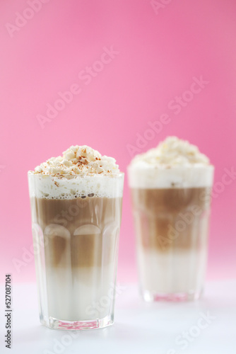 Close view of a tasty caramel milkshake on a pink background.