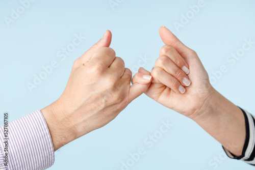 Two people making a bet in front of a blue background photo