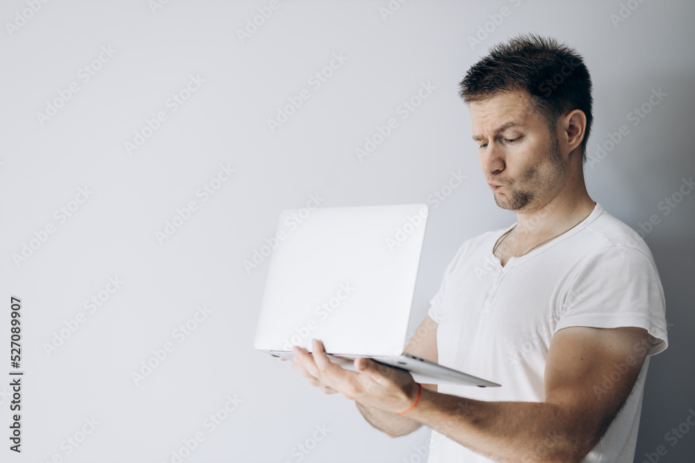 Guy programmer in a white t-shirt holds a laptop Guy programmer in a white t-shirt holds a laptop
