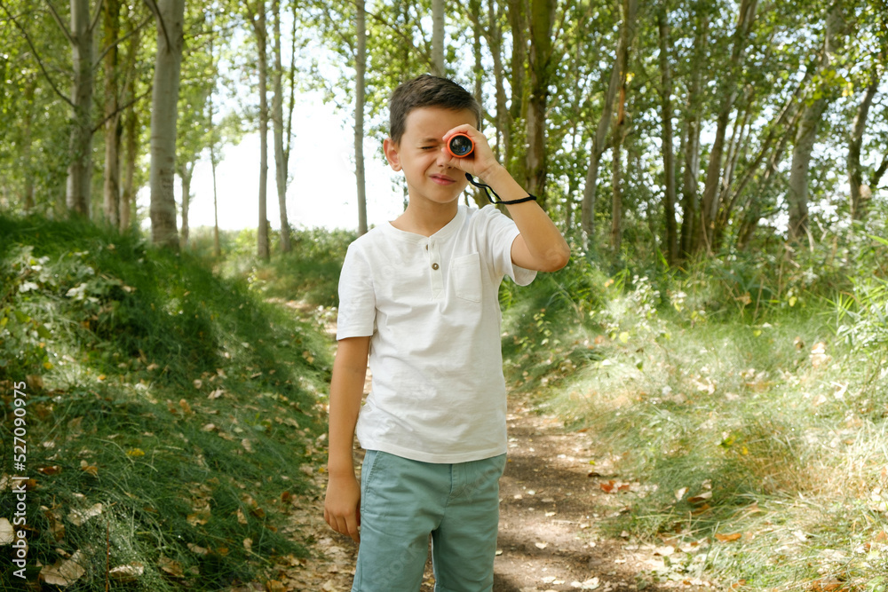child observes with monocle in nature looking at camera child observes with monocle in nature looking at camera