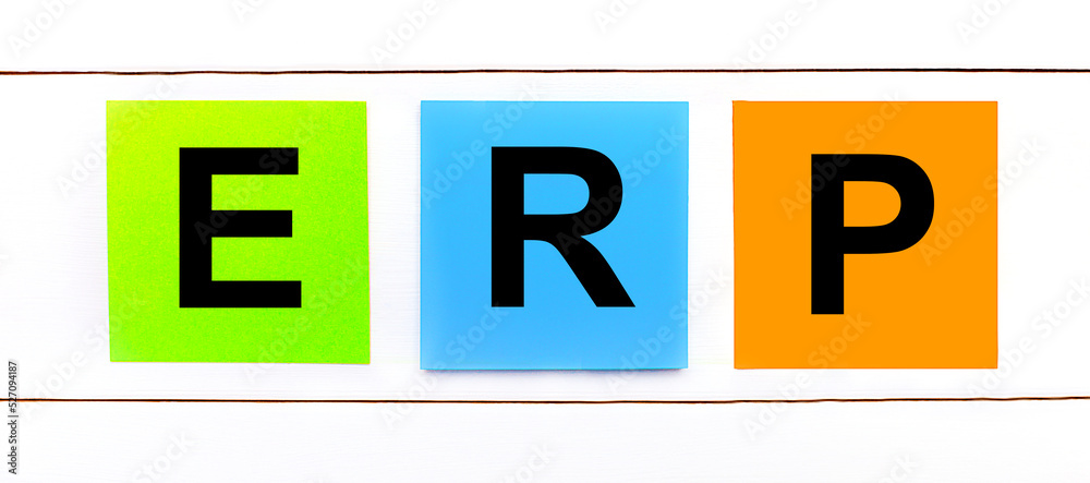 On a white wooden background there are three colorful bright stickers with text ERP Enterprise Resource Management On a white wooden background there are three colorful bright stickers with text ERP Enterprise Resource Management