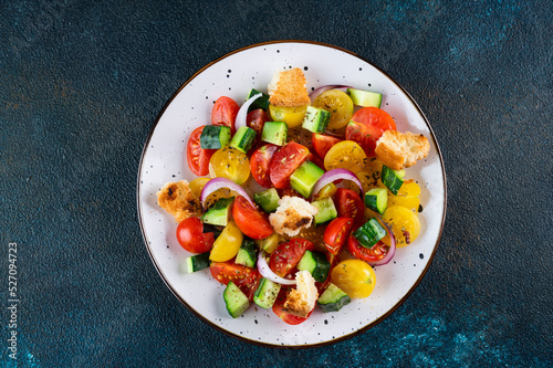 Vegetarian salad Panzanella with tomatoes, onion and bread Croutons. Dark background. Top view. Italian salad