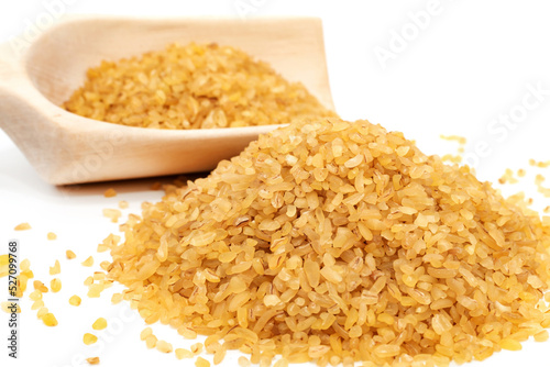 Bulgur wheat. Slide and scoop with grains of bulgur on a white background