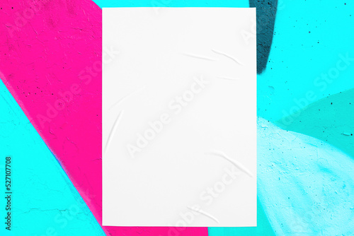 Closeup of colorful messy painted urban wall texture with wrinkled glued poster template. Modern mockup for design presentation. Creative pink mint green blue urban city background. 