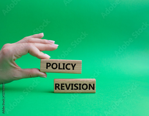Policy revision symbol. Concept word Policy revision on wooden blocks. Beautiful green background. Businessman hand. Business and Policy revision concept. Copy space