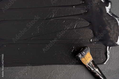 Fototapeta Naklejka Na Ścianę i Meble -  fondo de base de madera recién pintada de negro con pincel asomado con pintura negra fresca