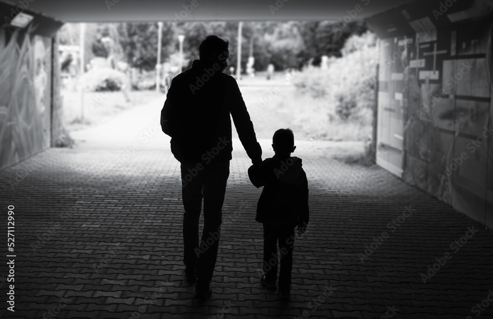 Father son relationship. Silhouette of father son walking his son  down a city street 