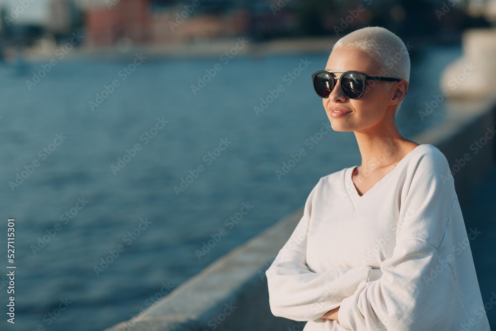 Portrait of young smiling millenial european short haired woman in sunglasses. Beautiful happy blonde girl outdoor. Summer fashion female clothing. Portrait of young smiling millenial european short haired woman in sunglasses. Beautiful happy blonde girl outdoor. Summer fashion female clothing.