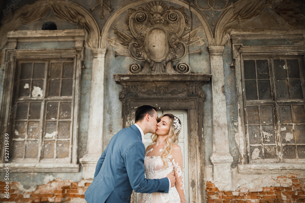 Beautiful bride and groom embracing and kissing on their wedding day outdoors Beautiful bride and groom embracing and kissing on their wedding day outdoors