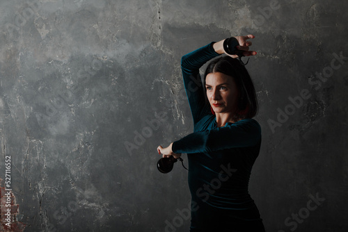 Young adult spanish woman with castanets dancing flamenco on gray vintage studio background photo
