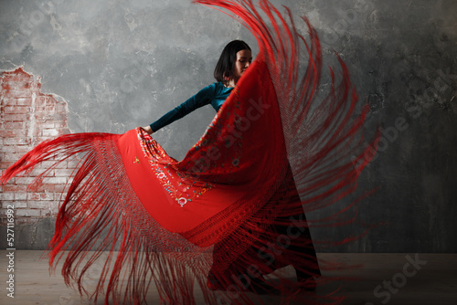 Young adult spanish woman dancing flamenco on gray vintage studio background