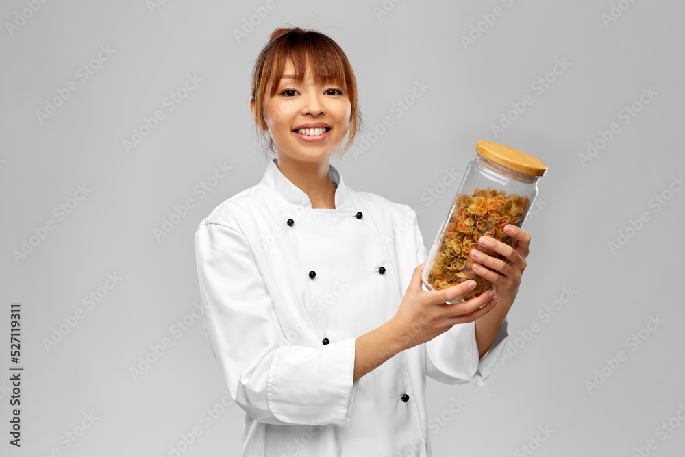 cooking, culinary and people concept - happy smiling female chef holding jar with pasta over grey background cooking, culinary and people concept - happy smiling female chef holding jar with pasta over grey background