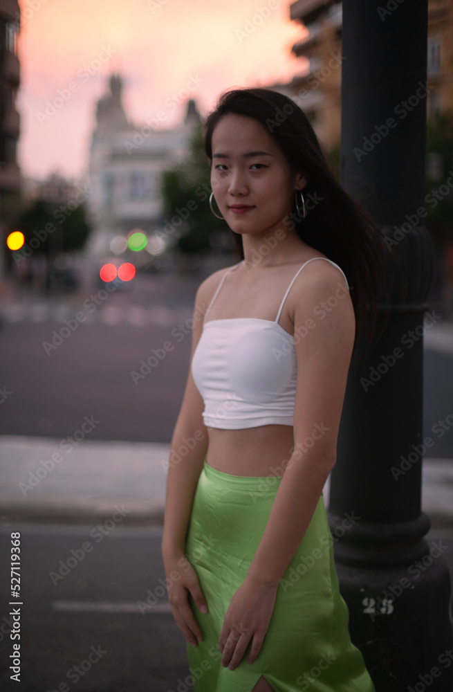 Beautiful Asian woman walking the night street of European city while traveling. Tourist from China exploring. Diverse people and tourism in Europe, fashion and style concept.
