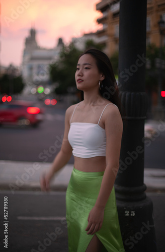 Beautiful Asian woman walking the night street of European city while traveling. Tourist from China exploring. Diverse people and tourism in Europe, fashion and style concept.