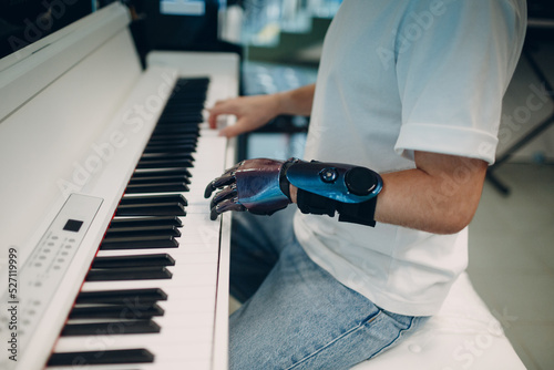 Young disabled man play on piano electronic synthesizer with artificial prosthetic hand in music shop